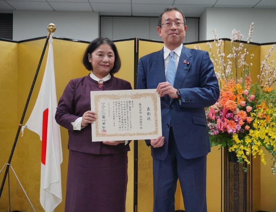 表彰状を持ち、記念写真をする河合祐子頭取の写真