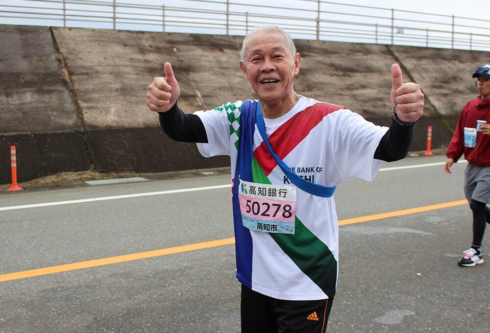 笑顔でペアリレーを走る「高知銀行海治会長」の写真